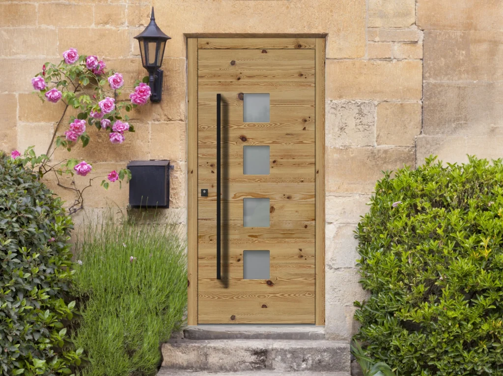 Spitfire aluminium entrance door in a light green wood-effect finish, fitted to a traditional English limestone cottage with climbing roses
